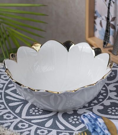 Antique off-white ceramic serving bowl placed on a wooden dining table.