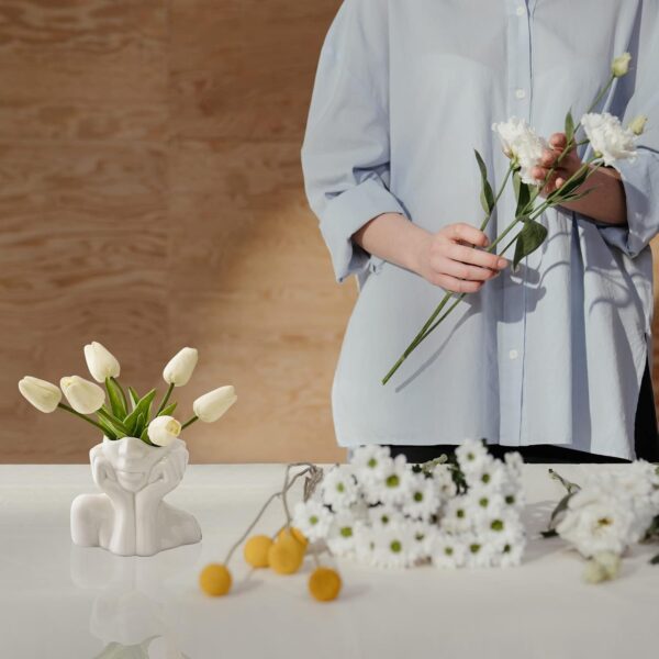 Stylish white ceramic vase featuring abstract facial art design