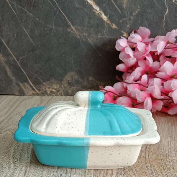 Elegant white ceramic butter dish with wooden lid on kitchen counter