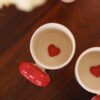 Love-themed ceramic coffee mug with a red heart handle and heart inside, ideal for couples.