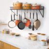 Black metal kitchen rack mounted on wall organizing pots and pans