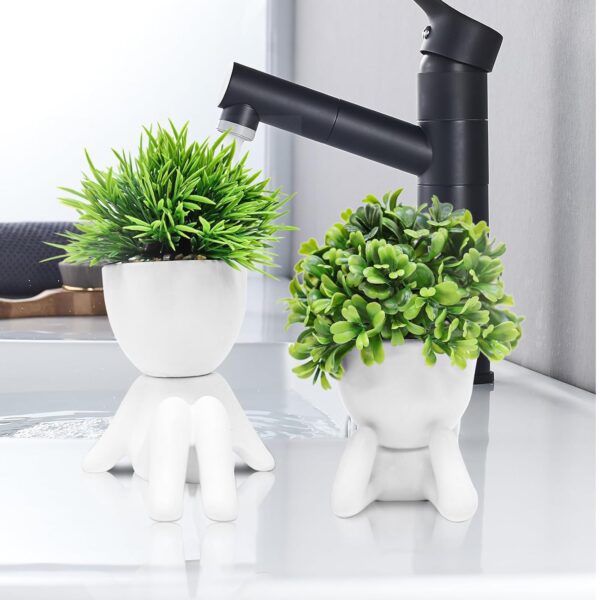 White ceramic human-style planters holding lifelike artificial succulents for interior design.