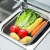 Expandable over-the-sink stainless steel drain basket for fruits and vegetables.