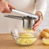 Manual stainless steel hand press juicer placed on a kitchen countertop