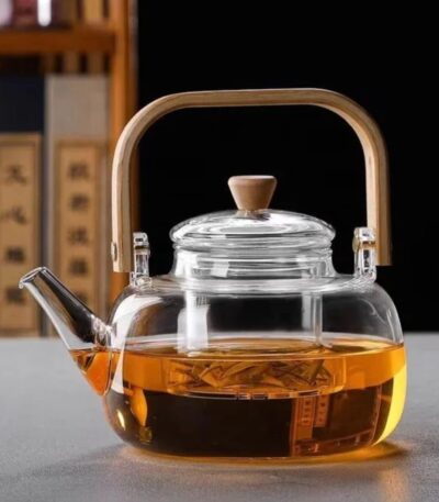Clear borosilicate glass teapot with infuser and wooden handle on white background