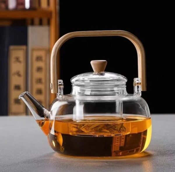 Clear borosilicate glass teapot with infuser and wooden handle on white background