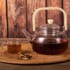 Elegant glass teapot with wooden handle placed on modern kitchen counter