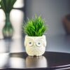 Small artificial fern plant in plastic owl planter for desk